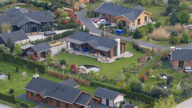 Aerial view of Ecodorp Bolderburen eco village featuring modern wooden houses with dark rooftops lush green gardens and a small pond in Almere Flevoland Netherlands. Aerial view of Ecodorp Bolderburen eco village featuring modern wooden houses with dark rooftops lush green gardens and a small pond in Almere Flevoland Netherlands.