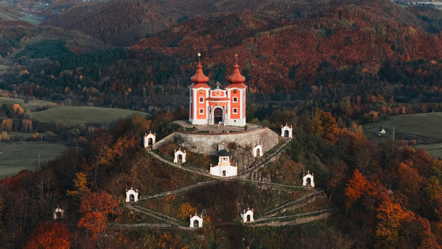 Aerial view of the red baroque church of Kalvaria Banska Stiavnica on a hill surrounded by autumn forests in Banska Stiavnica Banskobystricky kraj Slovakia.