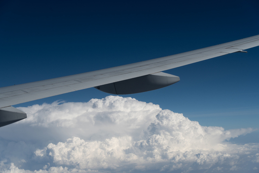 Aerial view of an airplane wing over towering white cumulonimbus clouds under a clear dark blue sky India. Aerial view of an airplane wing over towering white cumulonimbus clouds under a clear dark blue sky India.
