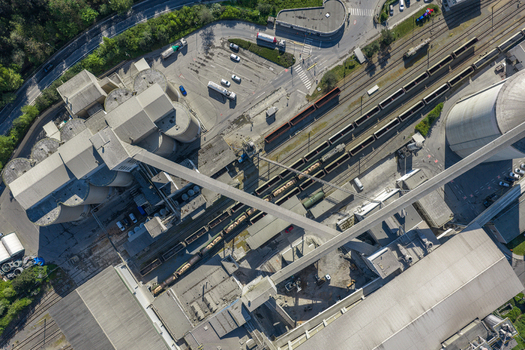 Aerial view of an industrial facility featuring large concrete silos long conveyor belts and railway tracks with freight trains in Prague Prague Czechia.