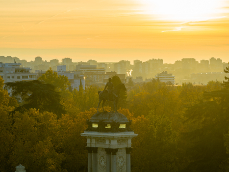 Aerial view of the Monument to Alfonso XII in El Retiro Park surrounded by autumn trees during golden hour with the city skyline in the background in Madrid Community of Madrid Spain.