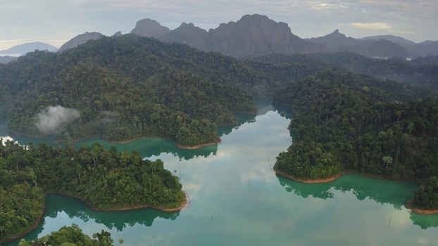 Aerial view of Khao Sok National Park featuring lush rainforest limestone karst mountains and calm turquoise waters of Cheow Lan Lake in Surat Thani Surat Thani Thailand. Aerial view of Khao Sok National Park featuring lush rainforest limestone karst mountains and calm turquoise waters of Cheow Lan Lake in Surat Thani Surat Thani Thailand.