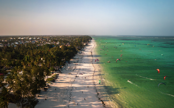 Aerial view of a vibrant beach bustling with kitesurfers where turquoise waters meet the white sands Paje Unguja South Region Tanzania. Aerial view of a vibrant beach bustling with kitesurfers where turquoise waters meet the white sands Paje Unguja South Region Tanzania.