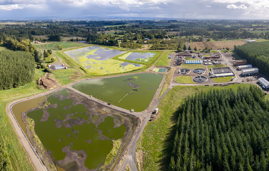 Aerial view of the wastewater treatment plant with large sedimentation ponds and industrial infrastructure surrounded by rural fields and forests in Woodburn Oregon United States. Aerial view of the wastewater treatment plant with large sedimentation ponds and industrial infrastructure surrounded by rural fields and forests in Woodburn Oregon United States.