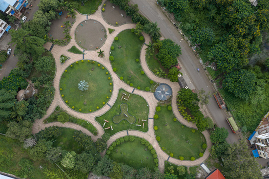 Aerial view of a public park in Karad featuring circular green lawns paved walkways and lush trees in Karad Maharashtra India.