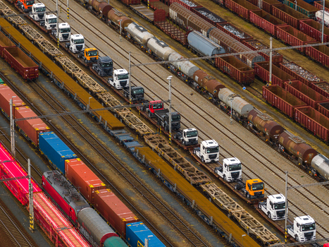 Aerial view of a busy railway yard featuring freight trains loaded with semi truck cabs and shipping containers in Breclav South Moravian Region Czechia.