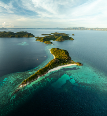 Aerial view of Malcapuya Island surrounded by turquoise coral reefs and deep blue sea in Coron Mimaropa Philippines. Aerial view of Malcapuya Island surrounded by turquoise coral reefs and deep blue sea in Coron Mimaropa Philippines.