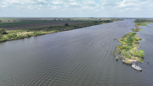 Aerial view of a wide reflective river curving through a landscape of green vegetation and distant fields Florida United States.