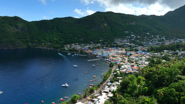 Aerial view of the coastal town of Soufriere nestled between lush green mountains and the Caribbean Sea with colorful houses and small boats in the bay Soufriere Soufriere Saint Lucia. Aerial view of the coastal town of Soufriere nestled between lush green mountains and the Caribbean Sea with colorful houses and small boats in the bay Soufriere Soufriere Saint Lucia.