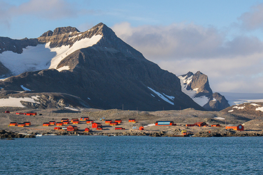 View of the red buildings of Esperanza Base set against snow capped mountains and the Antarctic sea in Esperanza Base Antarctica. View of the red buildings of Esperanza Base set against snow capped mountains and the Antarctic sea in Esperanza Base Antarctica.