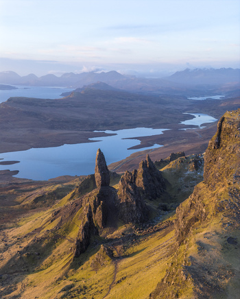 Aerial view of The Storr rock formation overlooking the lochs and rugged mountains under a soft sky Isle of Skye Scotland United Kingdom. Aerial view of The Storr rock formation overlooking the lochs and rugged mountains under a soft sky Isle of Skye Scotland United Kingdom.