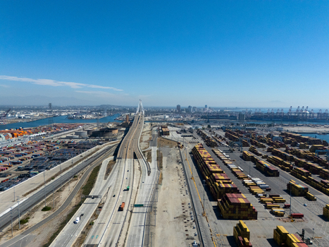 Aerial view of the Port of Long Beach featuring rows of shipping containers a highway bridge and industrial infrastructure under a clear blue sky in Long Beach California United States. Aerial view of the Port of Long Beach featuring rows of shipping containers a highway bridge and industrial infrastructure under a clear blue sky in Long Beach California United States.