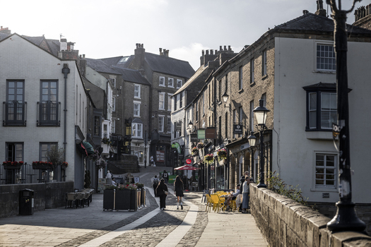 Durham United Kingdom 13 July 2026 View of a historic cobblestone street in Durham lined with traditional stone buildings shops and outdoor seating with people walking. Durham United Kingdom 13 July 2026 View of a historic cobblestone street in Durham lined with traditional stone buildings shops and outdoor seating with people walking.