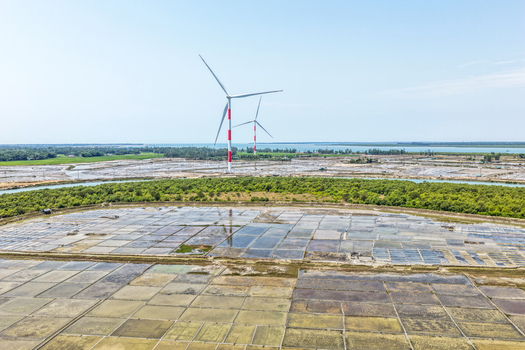 Aerial view of wind turbines casting long shadows over the patterned landscape creating a striking contrast between modern engineering and natural beauty Cox s Bazar Bangladesh. Aerial view of wind turbines casting long shadows over the patterned landscape creating a striking contrast between modern engineering and natural beauty Cox s Bazar Bangladesh.