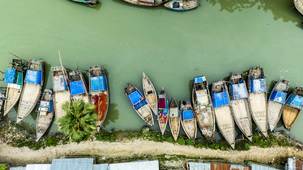Aerial view of traditional wooden fishing boats moored along the riverbank in Patharghata Barisal Division Bangladesh. Aerial view of traditional wooden fishing boats moored along the riverbank in Patharghata Barisal Division Bangladesh.