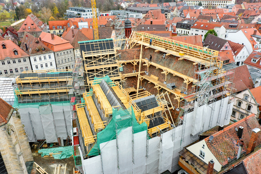 Aerial view of Rathaus Forchheim under renovation with extensive scaffolding and wooden framework surrounded by historic red roofed houses in Forchheim Bayern Germany. Aerial view of Rathaus Forchheim under renovation with extensive scaffolding and wooden framework surrounded by historic red roofed houses in Forchheim Bayern Germany.