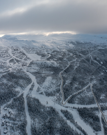 Aerial view of Gaustablikk Fjellresort nestled in the snow covered mountains with winding roads and ski slopes under a cloudy sky in Rjukan Telemark Norway. Aerial view of Gaustablikk Fjellresort nestled in the snow covered mountains with winding roads and ski slopes under a cloudy sky in Rjukan Telemark Norway.