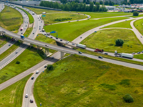 Aerial view of a complex highway interchange with multiple lanes overpasses and vehicles including trucks and cars surrounded by green grassy fields in Kaunas Kaunas County Lithuania.