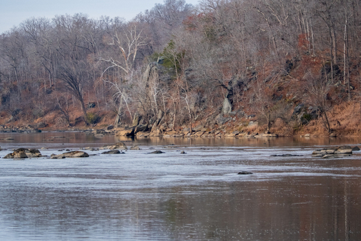 View of the serene river reflecting the muted colors of the bare trees and rocky banks under a soft winter sky Scott s Run Virginia United States. View of the serene river reflecting the muted colors of the bare trees and rocky banks under a soft winter sky Scott s Run Virginia United States.