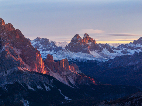 Aerial view of the Tre Cime di Lavaredo peaks ablaze with the rising sun s fiery hues Dolomites Italy.