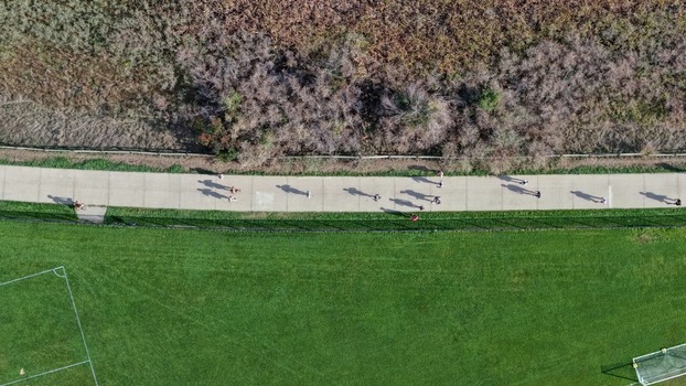 Aerial view of people walking and jogging along a paved path in a park with green grass and dry vegetation in Boulder Colorado United States. Aerial view of people walking and jogging along a paved path in a park with green grass and dry vegetation in Boulder Colorado United States.