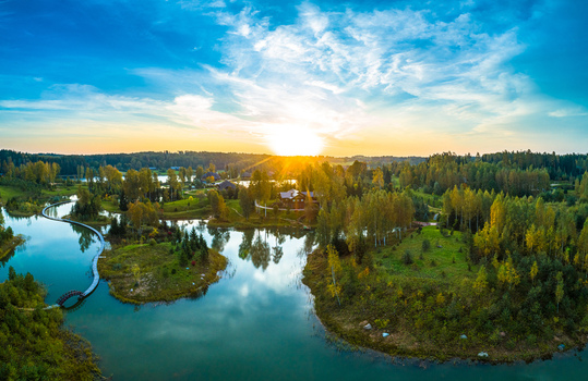 Aerial view of a serene lake with small islands wooden footbridges and lush forest under a vibrant golden hour sunset in Latvia. Aerial view of a serene lake with small islands wooden footbridges and lush forest under a vibrant golden hour sunset in Latvia.