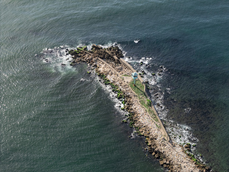Aerial view of a rocky breakwater extending into the sea with a small observation tower and crashing waves in Bajos de Haina San Cristobal Province Dominican Republic.