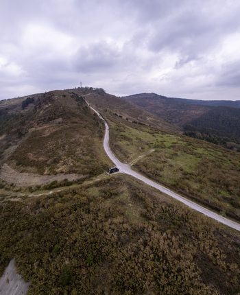 Aerial view of a camper van parked on a winding dirt road through the hilly landscape of Gaztelugatxeko Doniene Euskadi Spain. Aerial view of a camper van parked on a winding dirt road through the hilly landscape of Gaztelugatxeko Doniene Euskadi Spain.