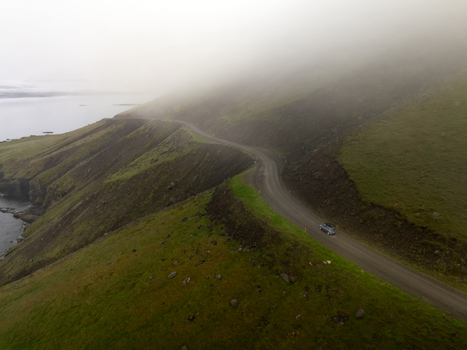 Aerial view of a winding gravel road along the coastal cliffs in the Eastern Region of Iceland. Aerial view of a winding gravel road along the coastal cliffs in the Eastern Region of Iceland.