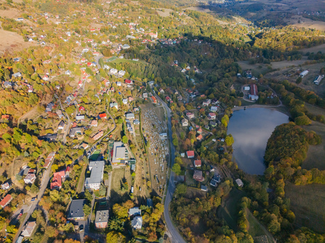 Aerial view of Evickino Lake surrounded by lush autumn forests residential houses and a cemetery in Stiavnicke Bane Banskobystricky kraj Slovakia.