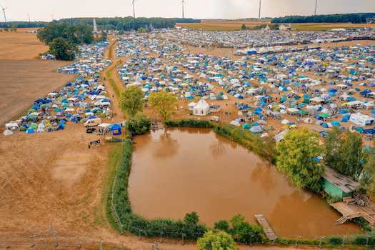 Aerial view of the Open Beatz Festival campsite featuring colorful tents a small pond and wind turbines in Herzogenaurach Bayern Germany. Aerial view of the Open Beatz Festival campsite featuring colorful tents a small pond and wind turbines in Herzogenaurach Bayern Germany.