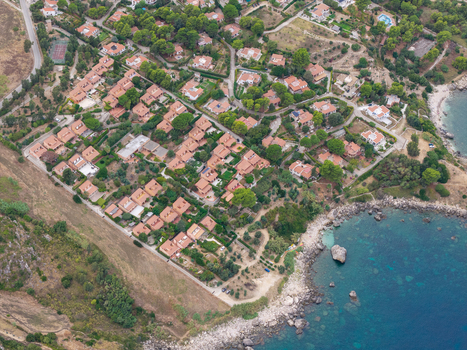 Aerial view of villas with terracotta roofs near Riserva Naturale Orientata dello Zingaro surrounded by lush trees and rocky coastline in San Vito Lo Capo Sicilia Italy. Aerial view of villas with terracotta roofs near Riserva Naturale Orientata dello Zingaro surrounded by lush trees and rocky coastline in San Vito Lo Capo Sicilia Italy.