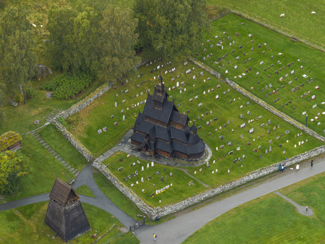 Aerial view of Borgund Stave Church surrounded by a historic cemetery with stone walls and lush green fields in Borgund Vestland Norway.