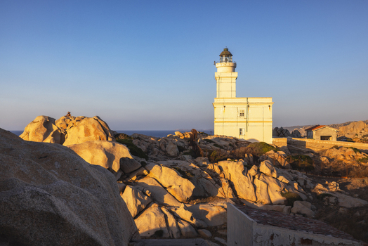 View of the Capo Testa lighthouse standing on rugged granite rock formations under a clear blue sky during golden hour Capo Testa Sardegna Italy. View of the Capo Testa lighthouse standing on rugged granite rock formations under a clear blue sky during golden hour Capo Testa Sardegna Italy.