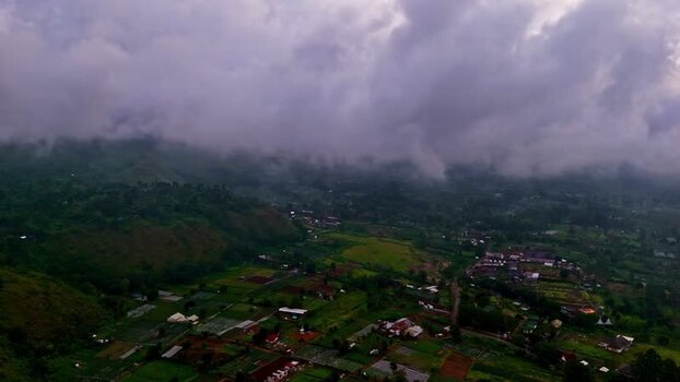Aerial view of lush green fields and misty hills in Bali Indonesia.