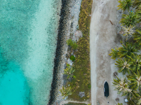 Aerial view of the turquoise sea meeting the sandy shore lined with lush green palm trees Vashafaru Island Thiladhummathi Atoll Maldives. Aerial view of the turquoise sea meeting the sandy shore lined with lush green palm trees Vashafaru Island Thiladhummathi Atoll Maldives.