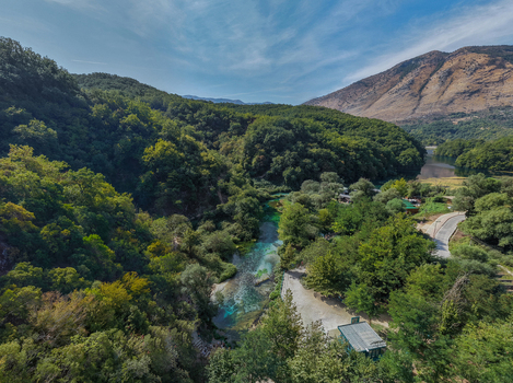 Aerial view of The Blue Eye a natural spring with vibrant turquoise water surrounded by lush green forests and mountains in Saranda Qarku i Vlores Albania. Aerial view of The Blue Eye a natural spring with vibrant turquoise water surrounded by lush green forests and mountains in Saranda Qarku i Vlores Albania.