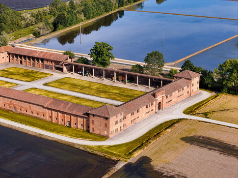 Aerial view of the historic Tenuta Colombara farm complex with its red brick buildings and flooded rice paddies in Livorno Ferraris Piemonte Italy.