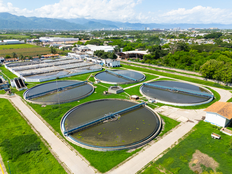 Aerial view of circular water treatment tanks amidst lush greenery juxtaposed with industrial buildings and distant mountains Puerto Vallarta Mexico. Aerial view of circular water treatment tanks amidst lush greenery juxtaposed with industrial buildings and distant mountains Puerto Vallarta Mexico.