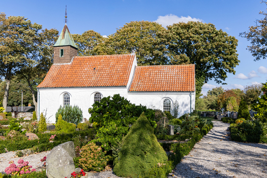 View of Hjarnoe Church with its white walls and red tiled roof surrounded by a lush cemetery in Hjarnoe Hedensted Municipality Denmark. View of Hjarnoe Church with its white walls and red tiled roof surrounded by a lush cemetery in Hjarnoe Hedensted Municipality Denmark.