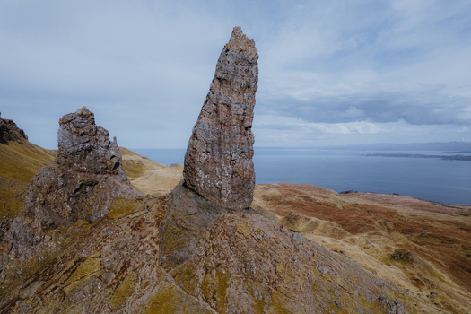 Aerial view of The Storr a dramatic rock pinnacle on the Isle of Skye surrounded by rugged grassy slopes and overlooking the sea in Portree Scotland United Kingdom. Aerial view of The Storr a dramatic rock pinnacle on the Isle of Skye surrounded by rugged grassy slopes and overlooking the sea in Portree Scotland United Kingdom.