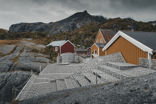 Nusfjord Norway 07 September 2022 View of Nusfjord a historic fishing village with traditional red and yellow wooden houses set against rocky terrain and dramatic mountains. Nusfjord Norway 07 September 2022 View of Nusfjord a historic fishing village with traditional red and yellow wooden houses set against rocky terrain and dramatic mountains.