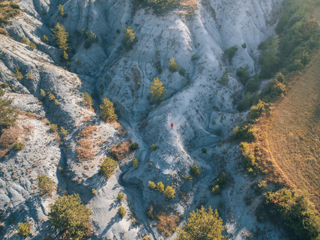 Aerial view of barren eroded landscape with sparse trees a lone figure standing amidst the textures Mende Occitanie France. Aerial view of barren eroded landscape with sparse trees a lone figure standing amidst the textures Mende Occitanie France.