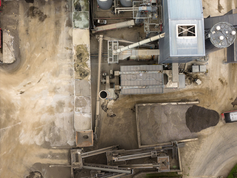 Aerial view of an industrial plant featuring conveyor belts silos and piles of gravel on a dusty ground in San Giovanni Valdarno Tuscany Italy.