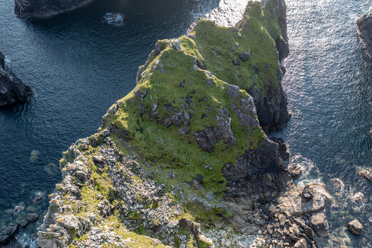 Aerial view of Glenlough Bay featuring rugged cliffs grassy slopes and deep blue Atlantic waters in Ardara County Donegal Ireland.