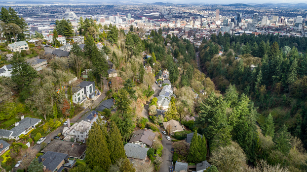 Aerial view of Northwest Imperial Terrace residential neighborhood nestled among lush evergreen trees with the city skyline in the distance in Portland Oregon United States. Aerial view of Northwest Imperial Terrace residential neighborhood nestled among lush evergreen trees with the city skyline in the distance in Portland Oregon United States.