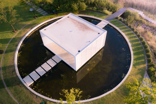 Aerial view of a modern white pavilion centered in a circular pond surrounded by lush green gardens and manicured lawns during golden hour in Cape Town Western Cape South Africa. Aerial view of a modern white pavilion centered in a circular pond surrounded by lush green gardens and manicured lawns during golden hour in Cape Town Western Cape South Africa.