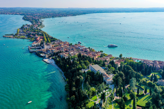 Aerial view of the Sirmione peninsula featuring Scaligero Castle and the turquoise waters of Lake Garda surrounded by lush greenery Italy. Aerial view of the Sirmione peninsula featuring Scaligero Castle and the turquoise waters of Lake Garda surrounded by lush greenery Italy.