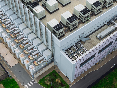 Aerial view of a data center rooftop featuring numerous industrial cooling units and HVAC systems arranged in rows on a flat roof in the United Kingdom.