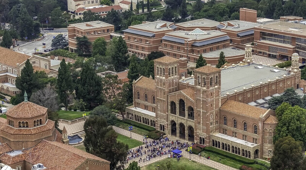 Aerial view of the historic UCLA Campus featuring the iconic Royce Hall with its twin towers surrounded by lush trees and red brick buildings in Westwood California United States.